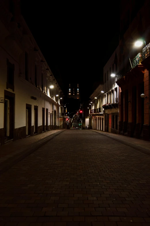 an empty brick street with lights on it at night