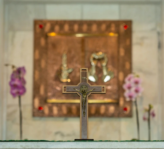 a cross sitting on top of a table with flowers