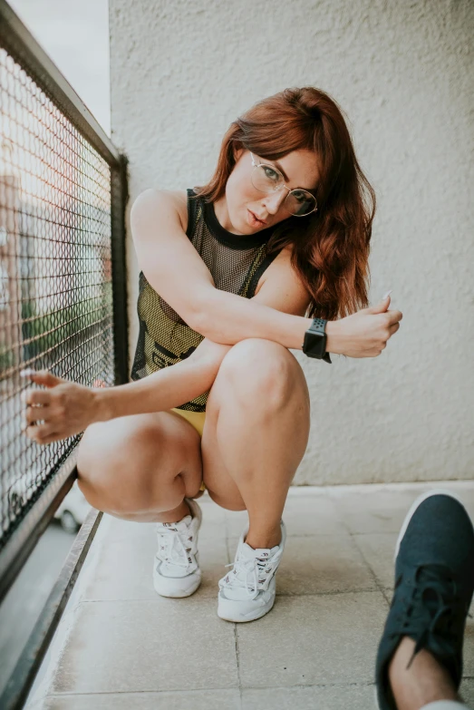 a woman sitting on a ledge wearing white sneakers