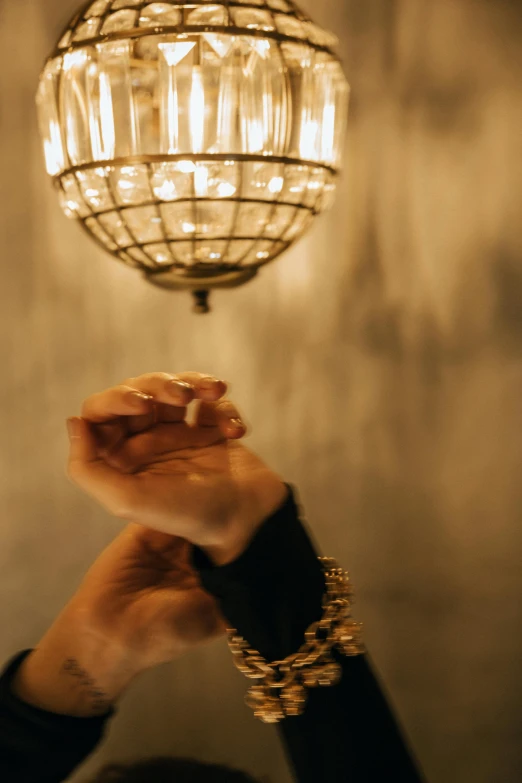 a woman holding up a hand that is touching the light above her head