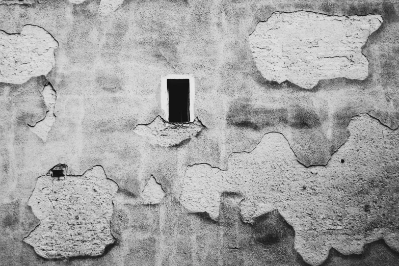 black and white image of a grated wall with a small window