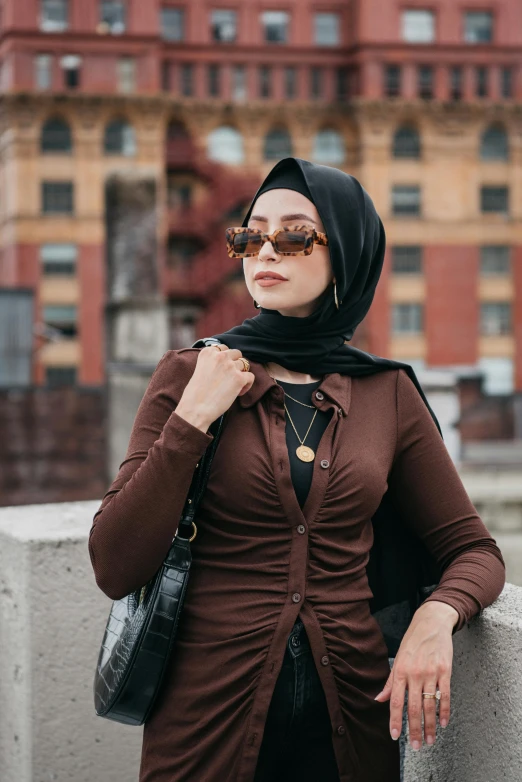 a woman leaning against a wall holding a purse