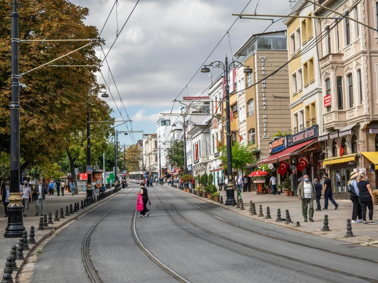 some people walk down the street, a road with power lines above