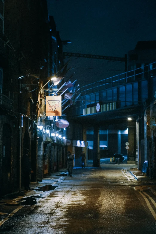 a dark alley street at night with a bus stop sign in the background