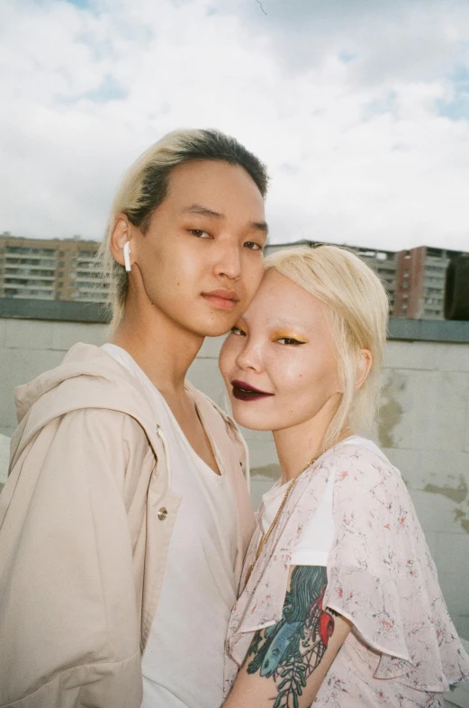 two people standing next to each other in front of buildings