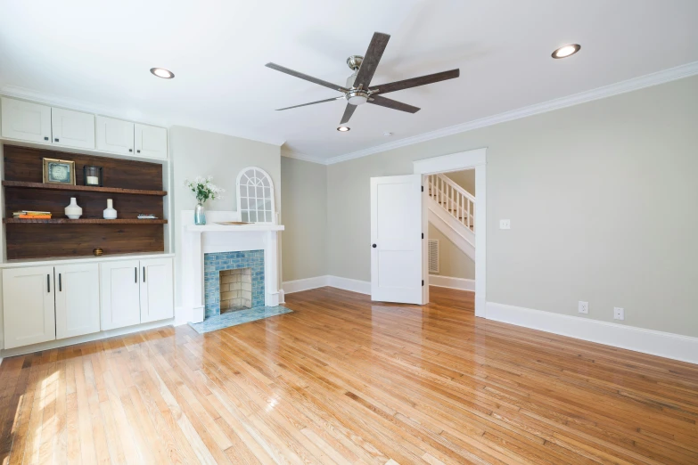 a living room filled with wooden floors and white cupboards