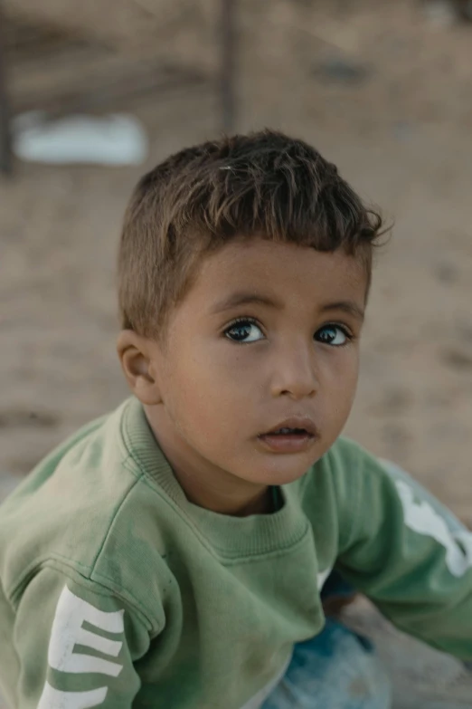 small boy looking at the camera on a sand area