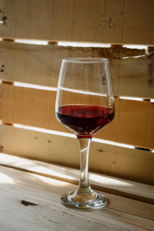 a wine glass filled with red wine sitting on a table