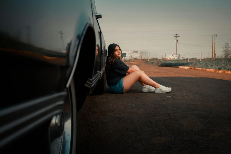 girl in shorts sitting on a car rim with the doors open