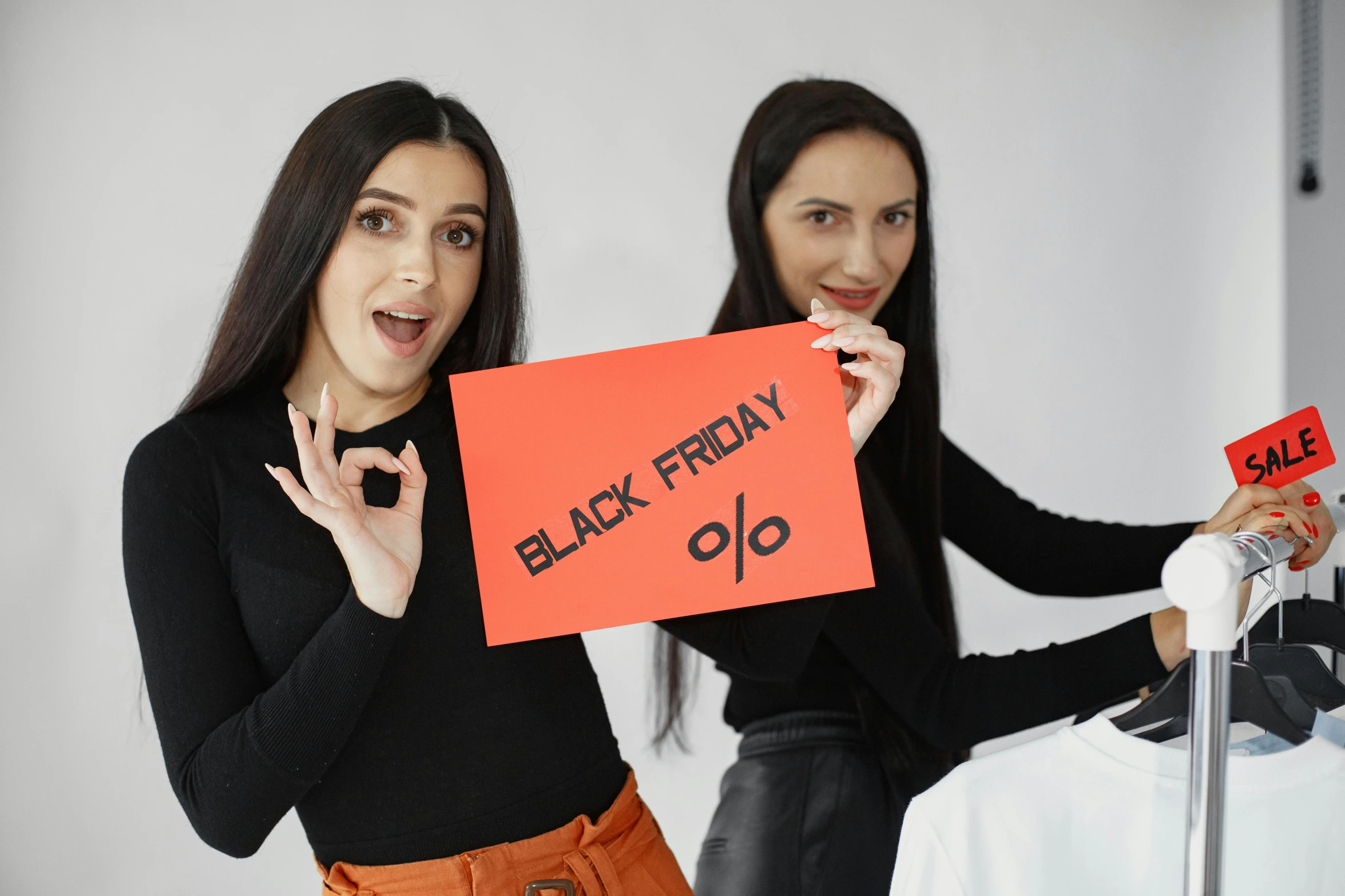 two women in black and red outfits holding a sign