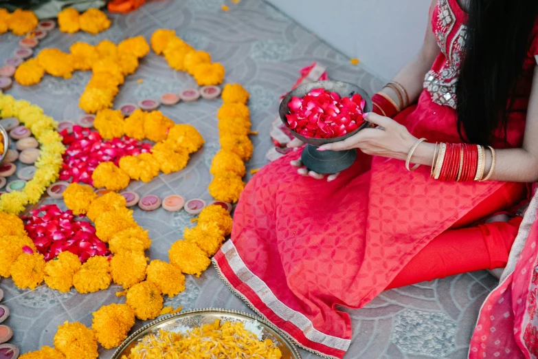 a woman sitting on the ground with orange flowers