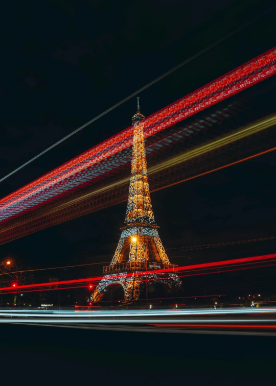 the eiffel tower at night with red streaks coming down it