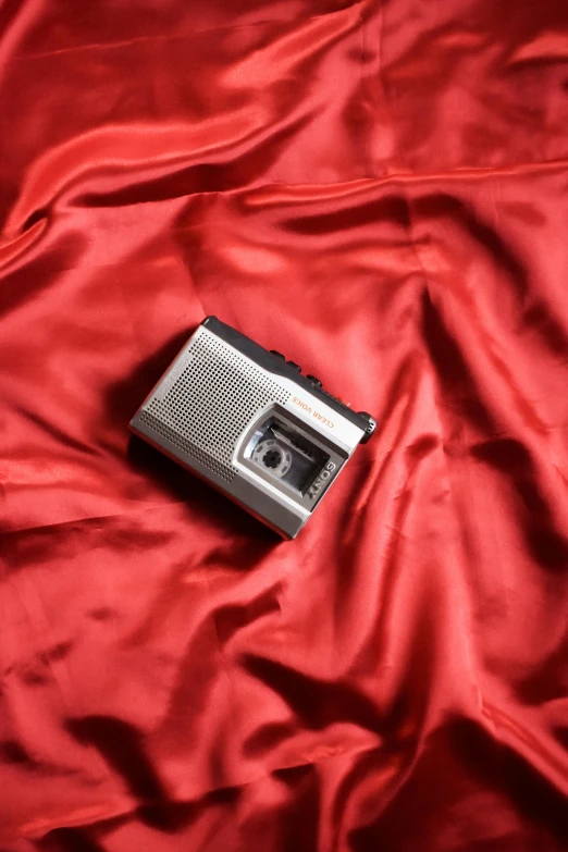 a cell phone on top of a bed covered with red satin