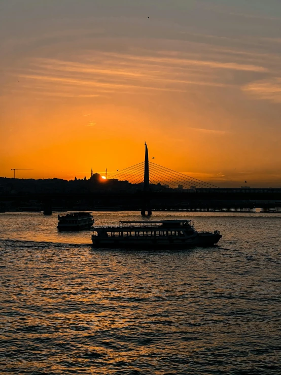 a sunset is lit over boats in the water