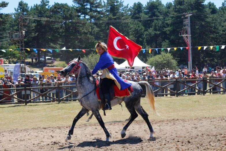 a woman dressed in blue riding a horse with a flag