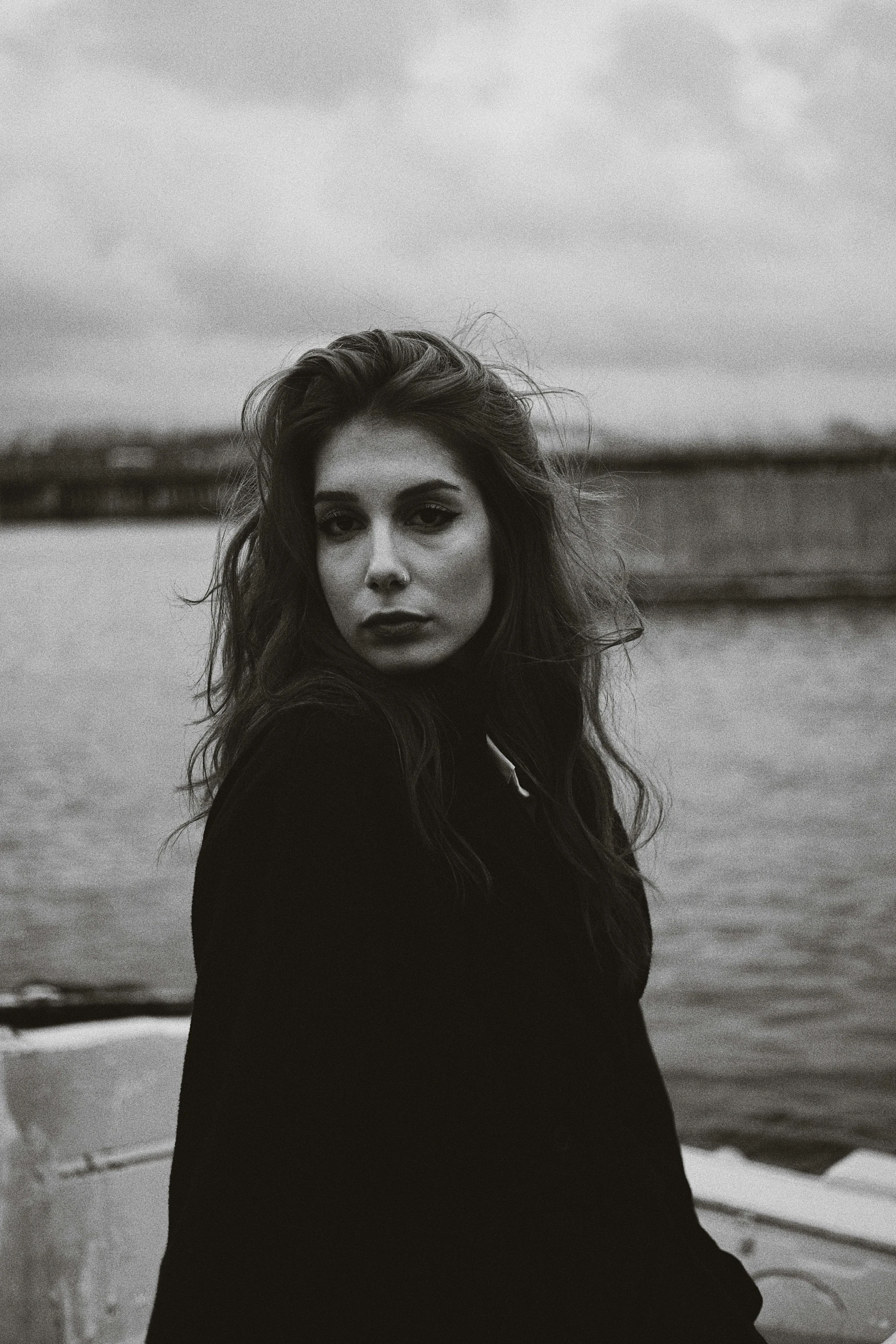 black and white portrait of a woman standing near a body of water