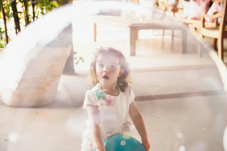 a little girl holding a green blue purse and smiling