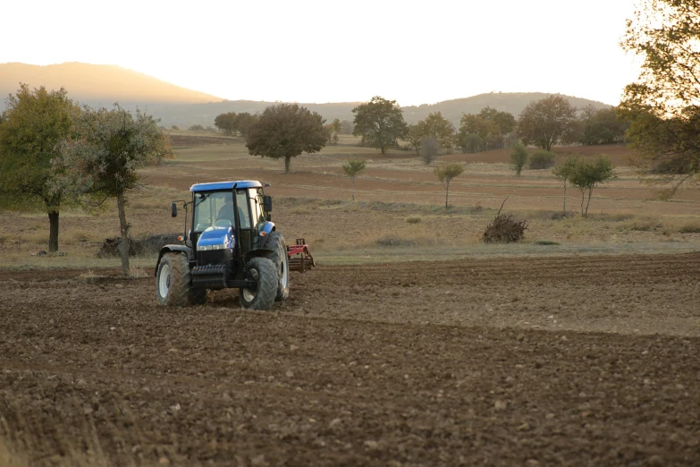 a blue tractor in the middle of a brown field