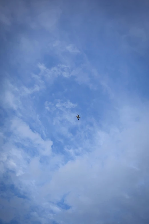 a plane flying across a cloudy blue sky