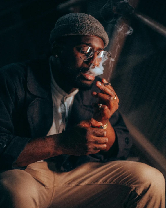 a man sitting down holding a cigarette