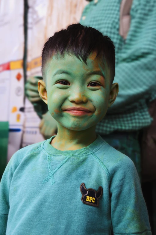 an asian child with dark hair and green makeup