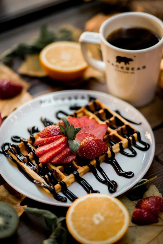 a plate of waffles covered with whipped cream, strawberries and orange slices