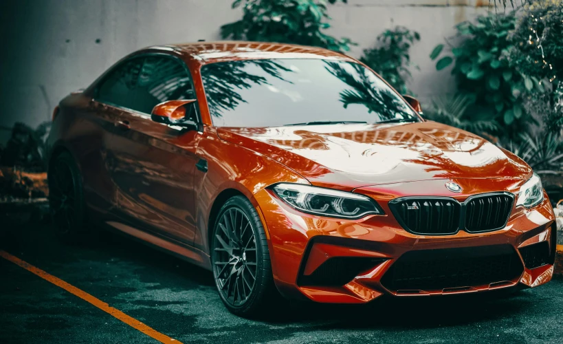 an orange bmw is parked in front of the wall