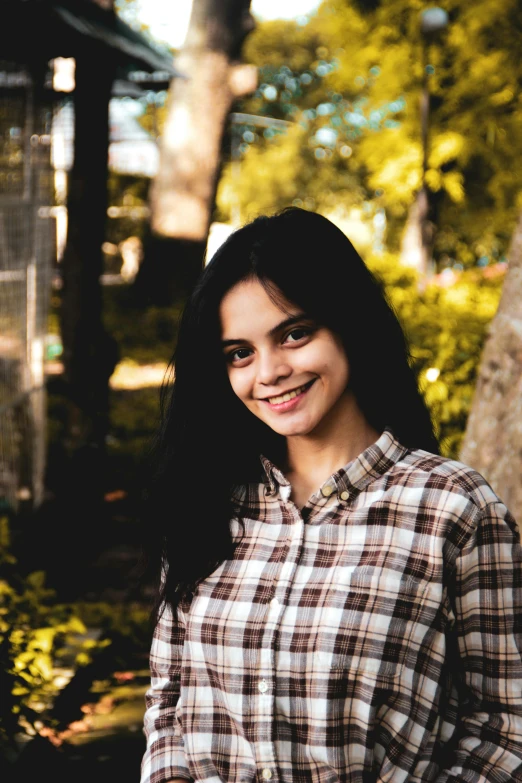 a  in plaid shirt smiling at the camera