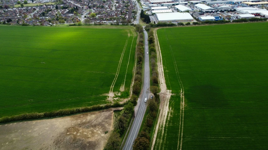 an aerial view of a road through green fields