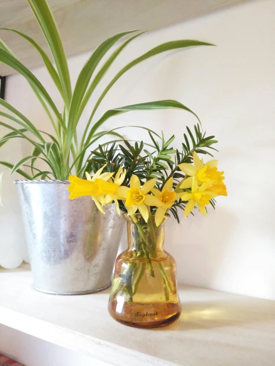 there is some yellow flowers in the vases on the mantel