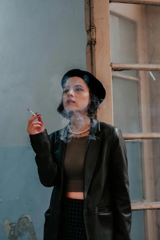 a woman wearing a black hat and smoking a cigarette