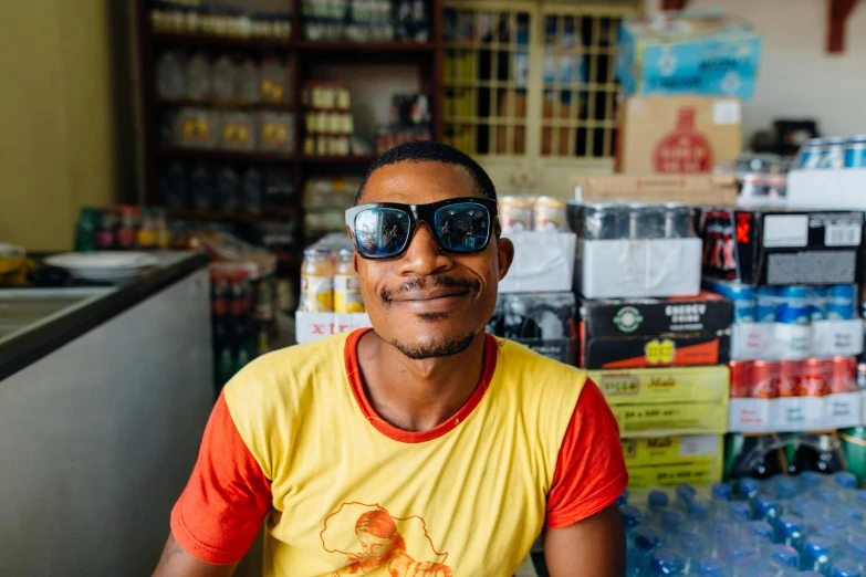 a man sits near many bottled drinks