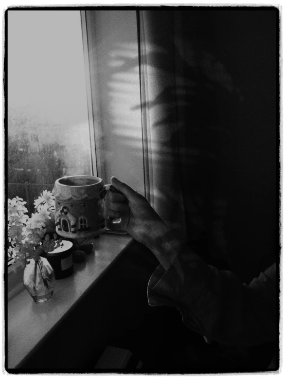 a hand is touching the window sill next to some flowers