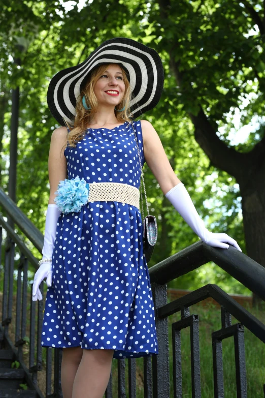 a woman wearing a large black hat and polka dotted dress