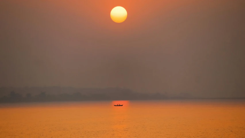 the sun rising over water with a small boat in the water