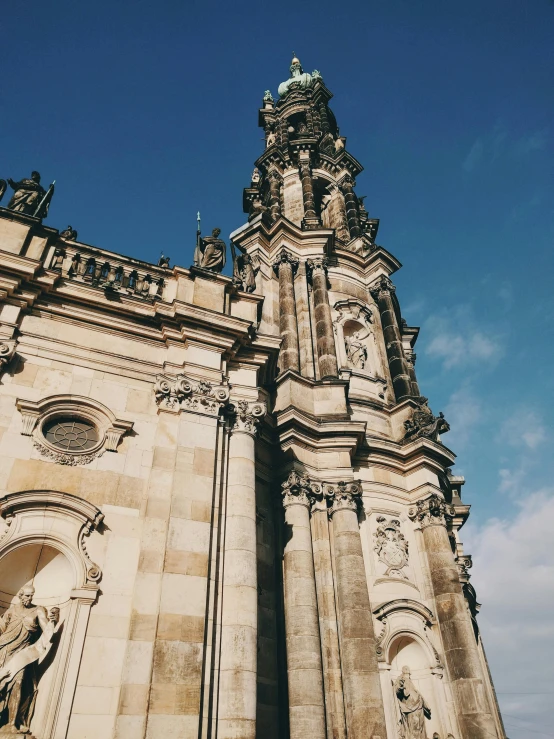 the very tall stone building has some statues on it