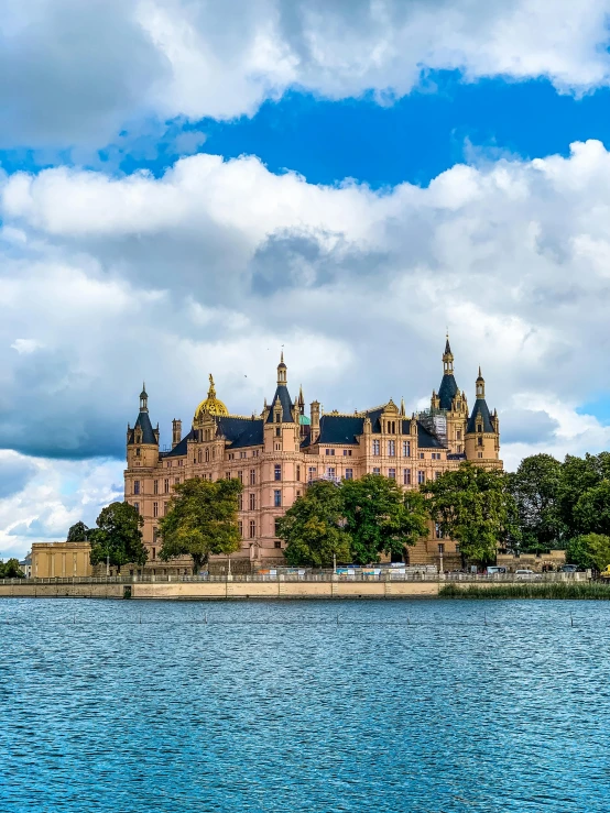 a very large castle next to the ocean under cloudy skies