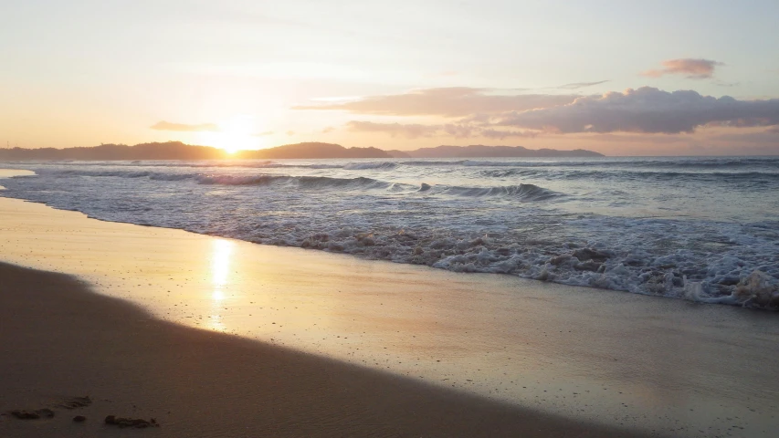 some footprints on the beach in front of a beautiful sunrise