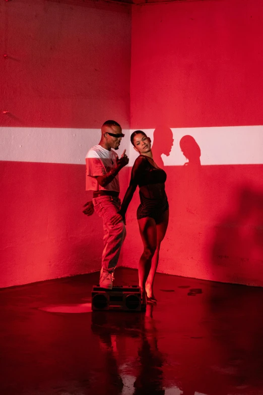a young couple dance on stage, in front of a red backdrop