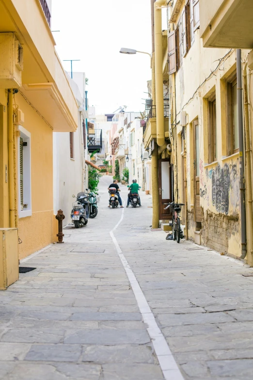 a man riding a motorcycle down a street next to another man