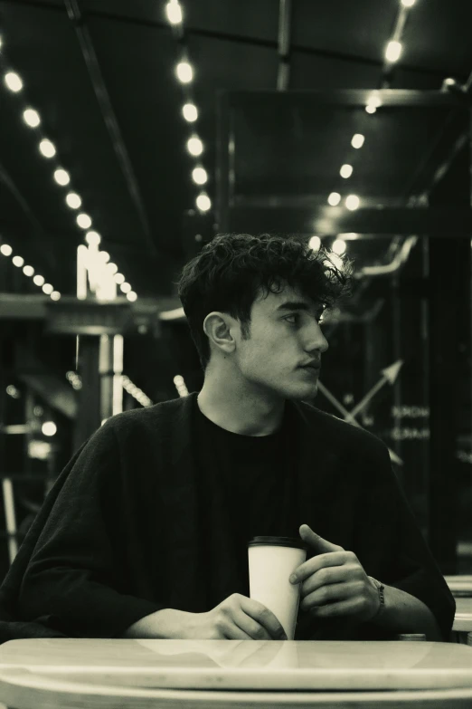 a man is sitting at a table drinking from a cup