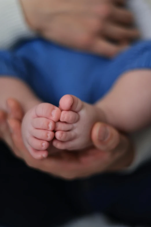 the hand of a baby laying in his mother's lap