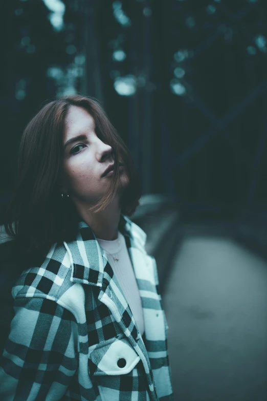 a woman wearing a plaid shirt in the middle of the forest