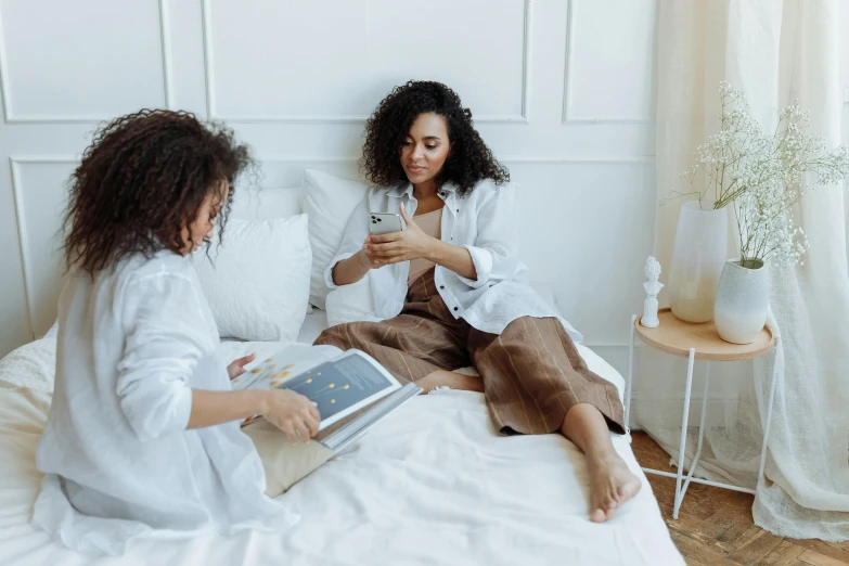 two women sitting on top of a bed