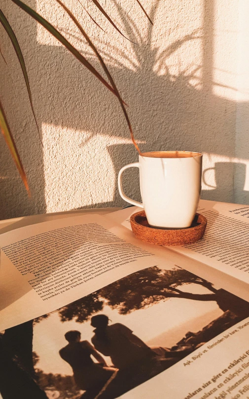 an open book and coffee cup on top of a table