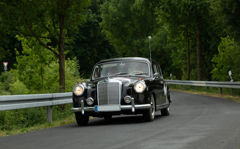 a vintage car drives down a country road