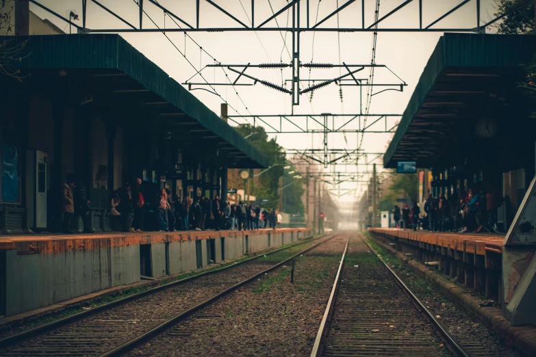 a train station with people on the platform and on the tracks