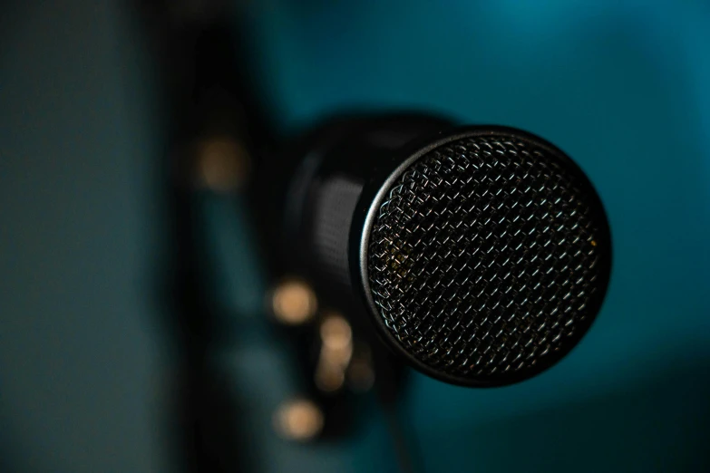 the top of a black microphone in front of a blue wall