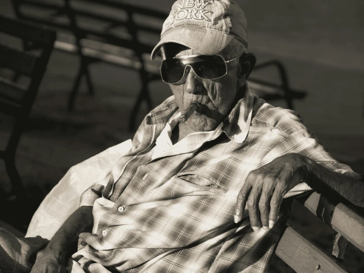 an older man with sunglasses on his head sitting on a bench