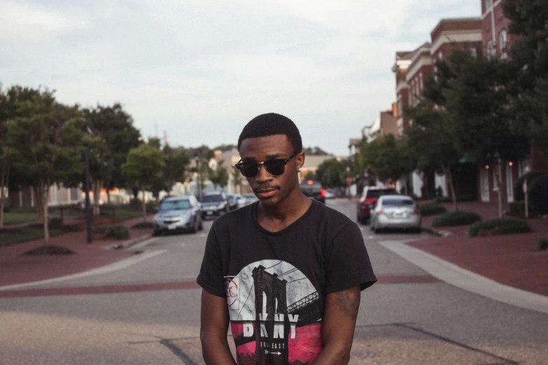 a young man holds a skateboard on a city street